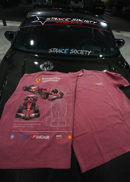A pair of Vintage Red t-shirts featuring a Ferrari Scuderia Ferrari F1 design, laid flat on the hood of a black car. The left shirt shows a detailed graphic of a red Formula 1 car, while the right shirt shows the plain back side.